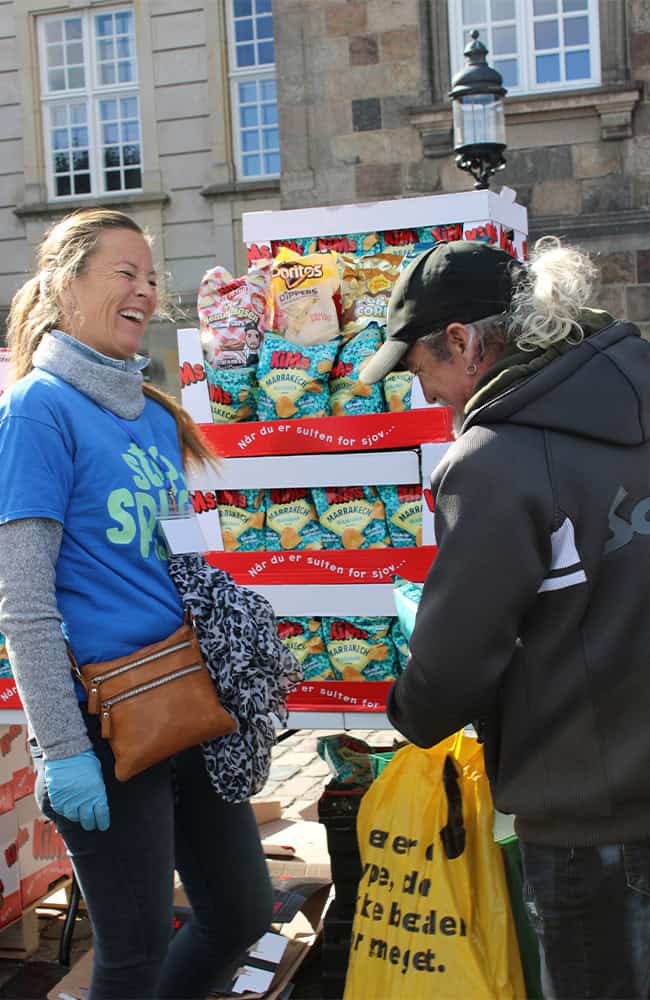 Frivillig uddeler overskudsmad Frivillig fra Stop Spild Lokalt uddeler overskudsmad til en besøgende